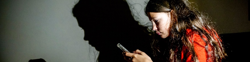 Mädchen sitzt und schaut auf ihr Handy