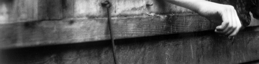 Jüdische Frau lehnt sich aus einer Holzbaracke in einem Konzentrationslager