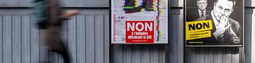 Eine Person geht an Plakaten der Kampagne „Nein zur Halbierung des SRG SSR“ vorbei. Die Slogans lauten: "Zerstörung des Zusammenhalts" und "Gegen die Volksinitiative 200 Franken sind genug"