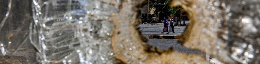 Zerstörtes Glas, dahinter Blick auf zwei Frauen im Sudan