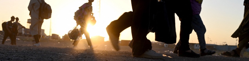 Menschen auf der Flucht bei einem Grenzübergang, Sonnenuntergang