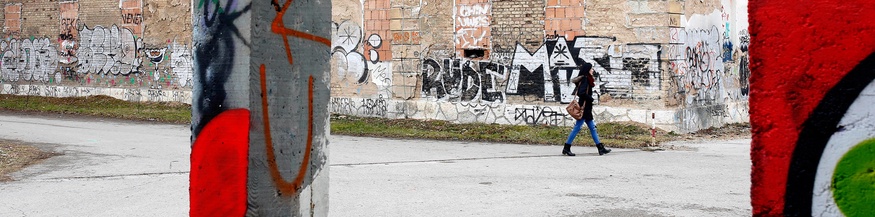 Alltagsaufnahme in Sarajevo, Frau geht an einer Ruine vorbei Graffiti