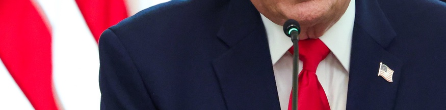 Donald Trumps Oberkörper und Mundpartie, dahinter US-Flagge