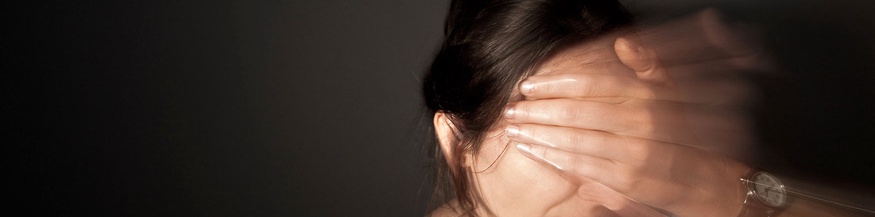 Frau hält sich Stirn