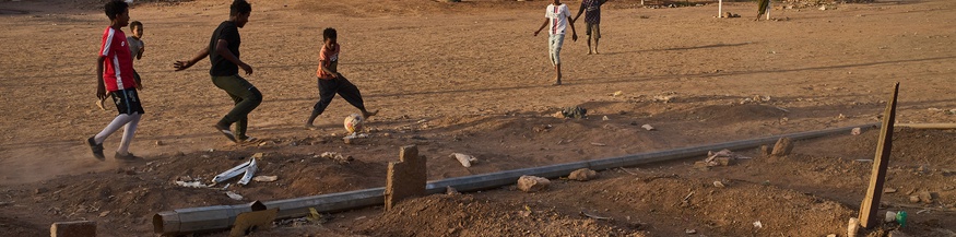 Buben spielen Fußball neben einem provisorischen Friedhof im Sudan