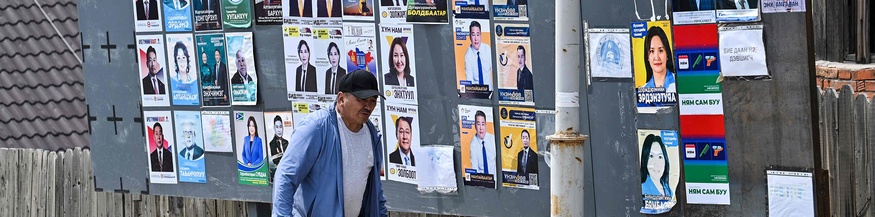 Mann geht an unterschiedlichen Wahlplakaten in der Mongolei vorbei