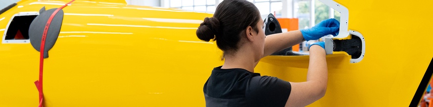 Eine weibliche Fachkraft montiert in einer Industriehalle etwas