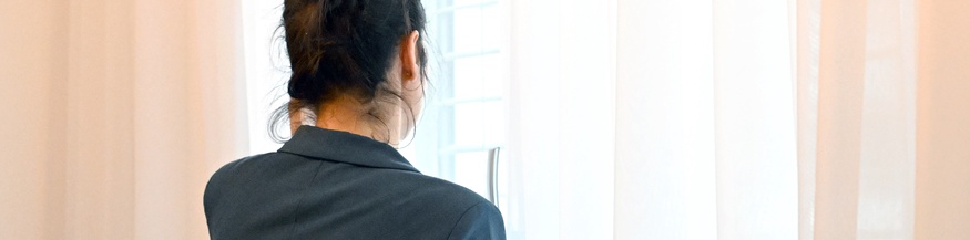 Frau schaut aus dem Fenster, Vorhang