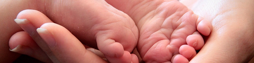 Frauenhand hält Babyfüße