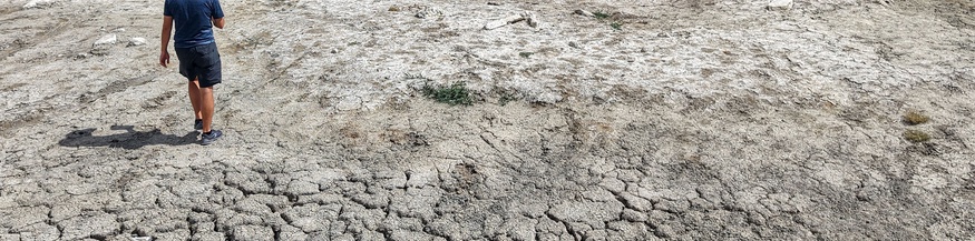 Mann geht über ausgetrockneten, aufgesprungenen Boden
