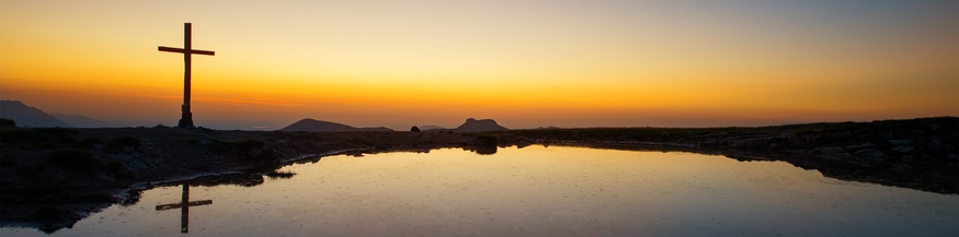 Gipfelkreuz auf einem Bergsee im Sonnenuntergang
