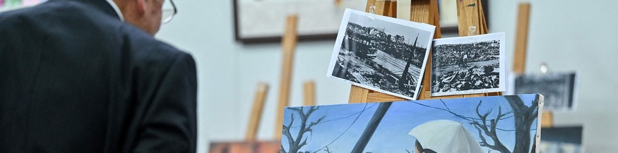 Atombomben-Überleber (Hibakusha) betrachtet Gemälde und alte Fotos
