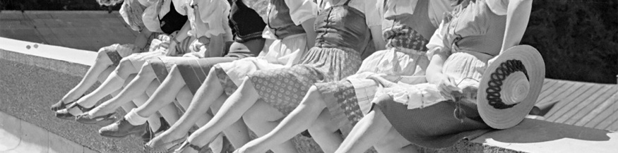 Frauen sitzen aufgereiht auf einer Steinmauer und posieren bei den Salzburger Festspielen 1946