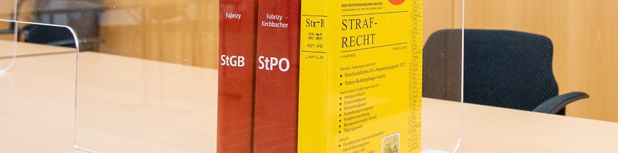 Gerichtssaal mit juristischen Sachbüchern: Kodex und StGB, StPO