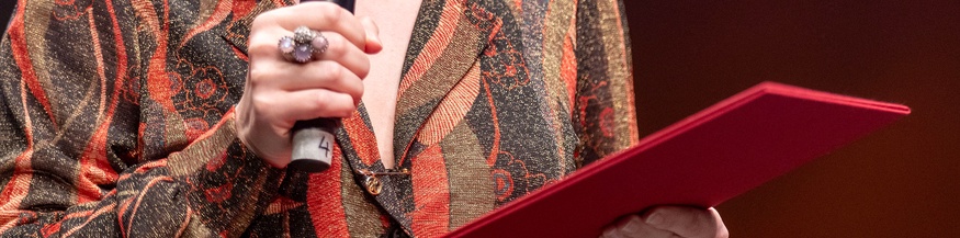 Frau hält Mappe und Mikrofon in Händen