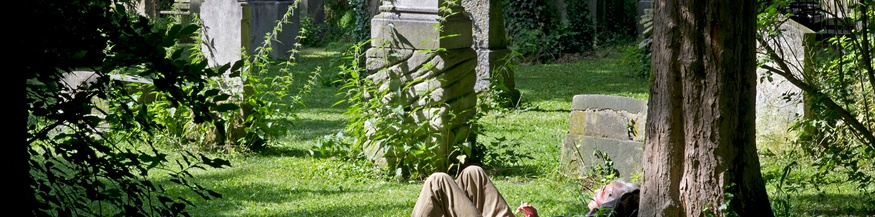 Ein Mann ruht sich am Friedhof aus.