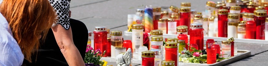 Menschen stellen Kerzen in Gedenken auf