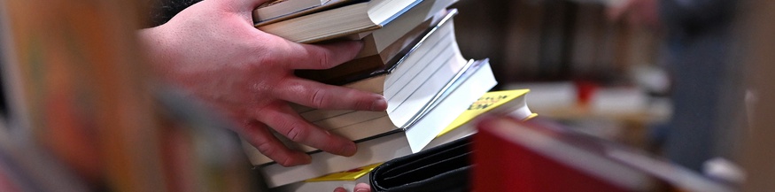 Eine Person hält einen Buchstapel in Händen auf der Leipziger Buchmesse
