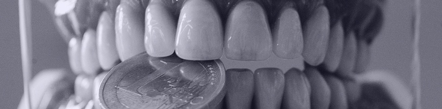 Künstliche Zähne beissen auf eine Ein-Euro Münze