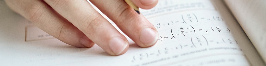 Hand mit Bleistift und Mathematikbuch