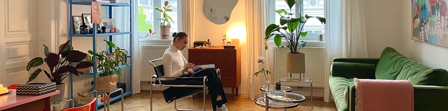 Eine Frau liest sitzend in ihrer Wohnung - "wie wien wohnt"