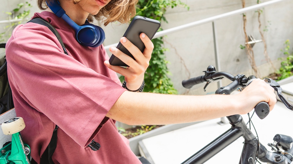 Bursche mit Fahrrad und Smartphone, Jugendlicher