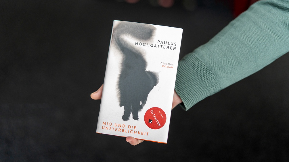 Das Buch "Mio und die Unsterblichkeit" wird in die Kamera von einer Männerhand gehalten
