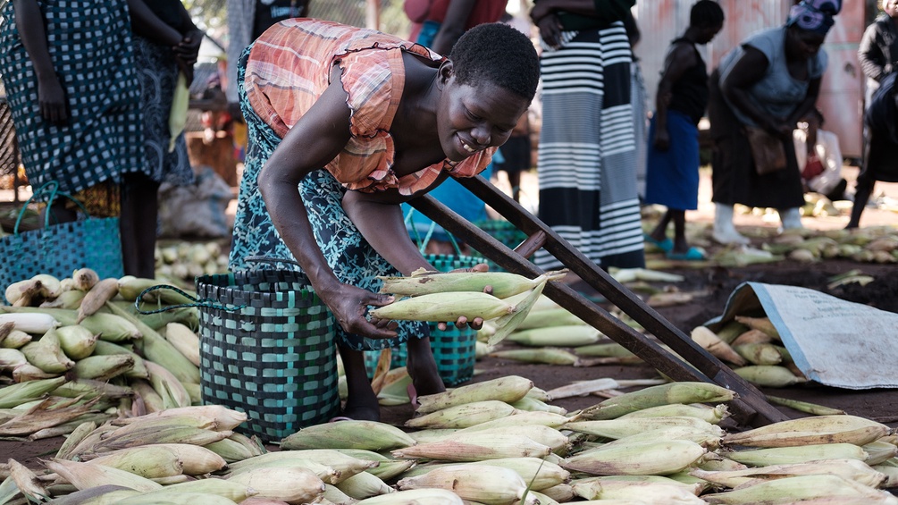 Frau mit Krücke verkauft Maiskolben