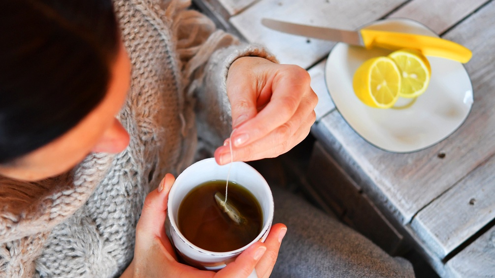 Eine Frau sitzt am Tisch mit Tee und Zitronen