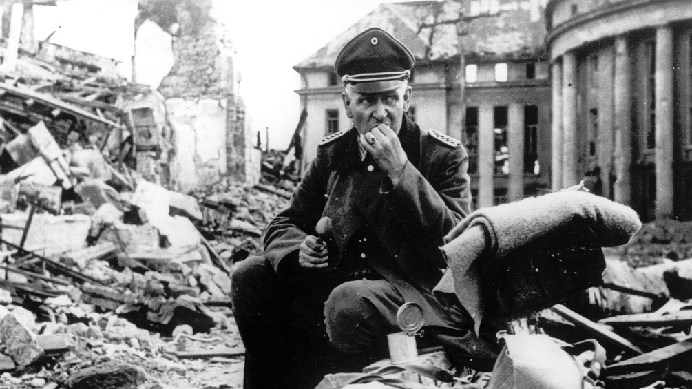 Wehrmachtsoffizier isst zwischen Trümmern