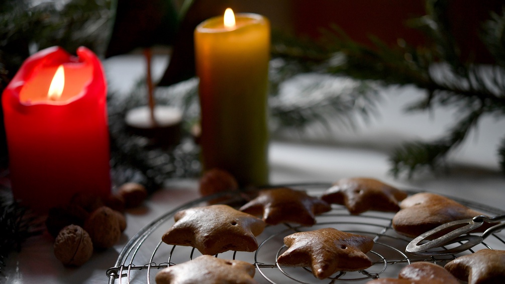 Kerzen und Kekse auf einem weihnachtlich geschmückten Tisch.
