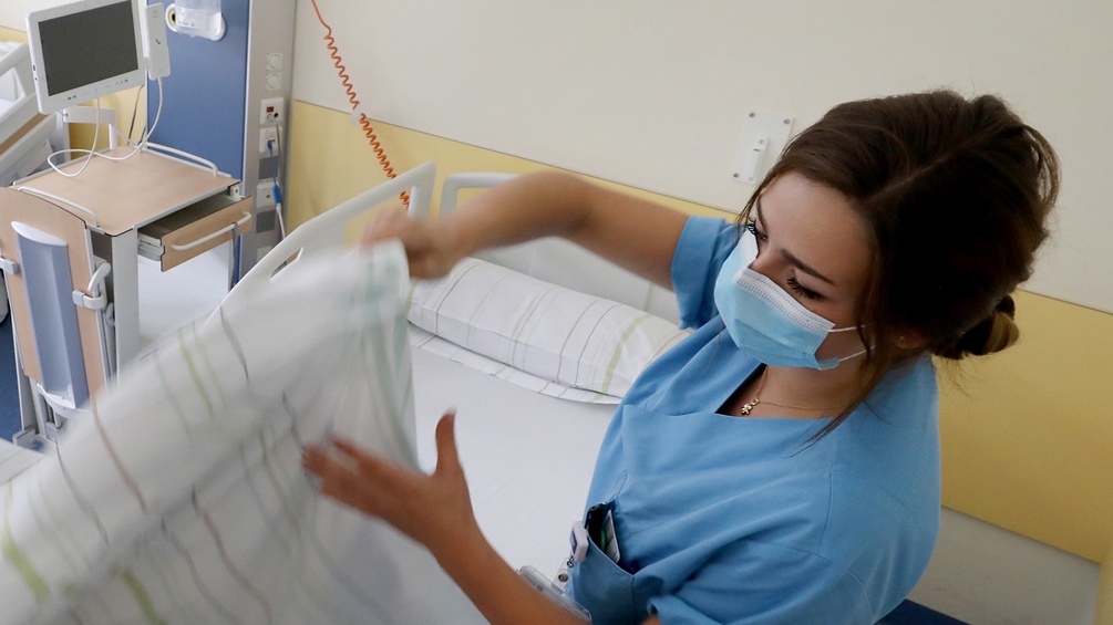 Pflege-Mitarbeiterin bezieht ein Krankenbett