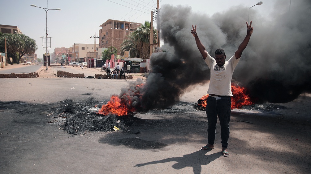Mann im Sudan vor brennender Straße