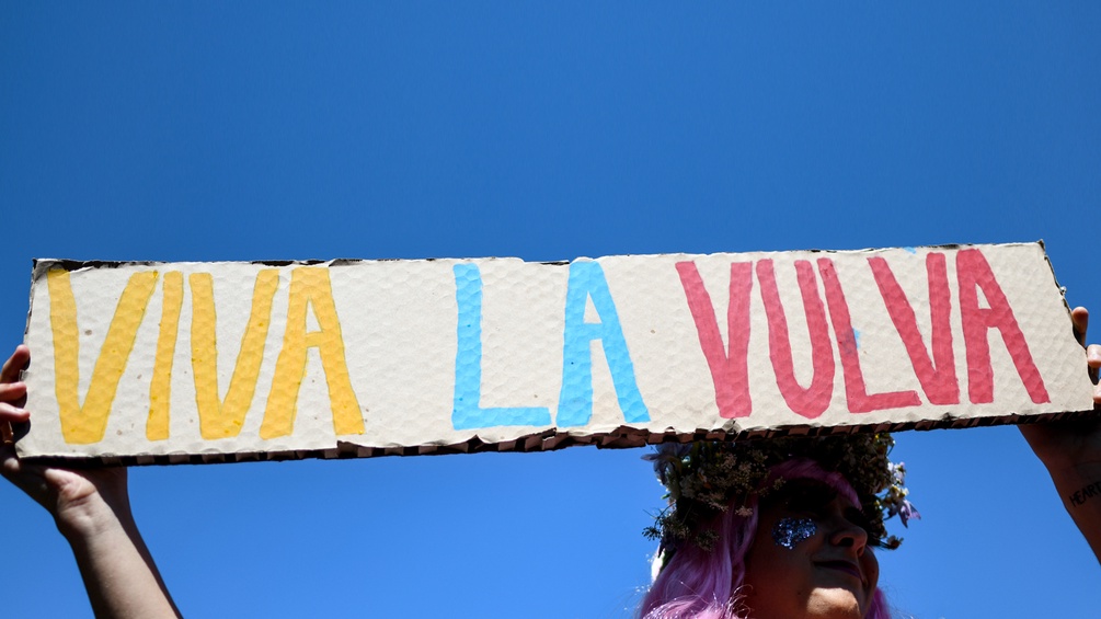 Eine Frau hält ein Schild in die Höhe mit der Auschrift: "Viva la Vulva".