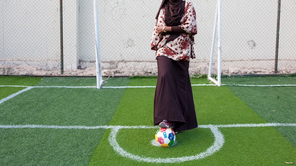 Eine Frau mit Schleier steht auf dem Fußballfeld.