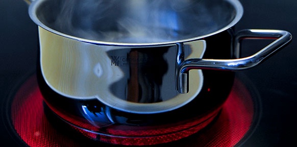 Ein Topf mit kochendem Wasser wird erhitzt durch das glühende Kochfeld