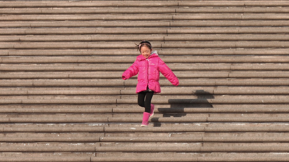 Ein Mädchen in rosa gekleidet läuft Stiegen runter