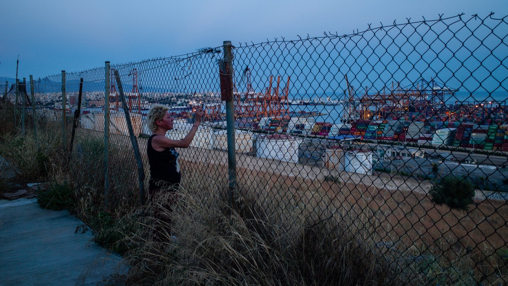 Eine arbeitslose Griechin steht vor einem Zaun nah zu Athen