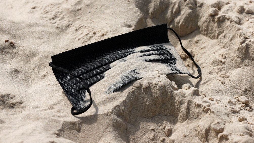 Eine schwarze Maske im Sand.