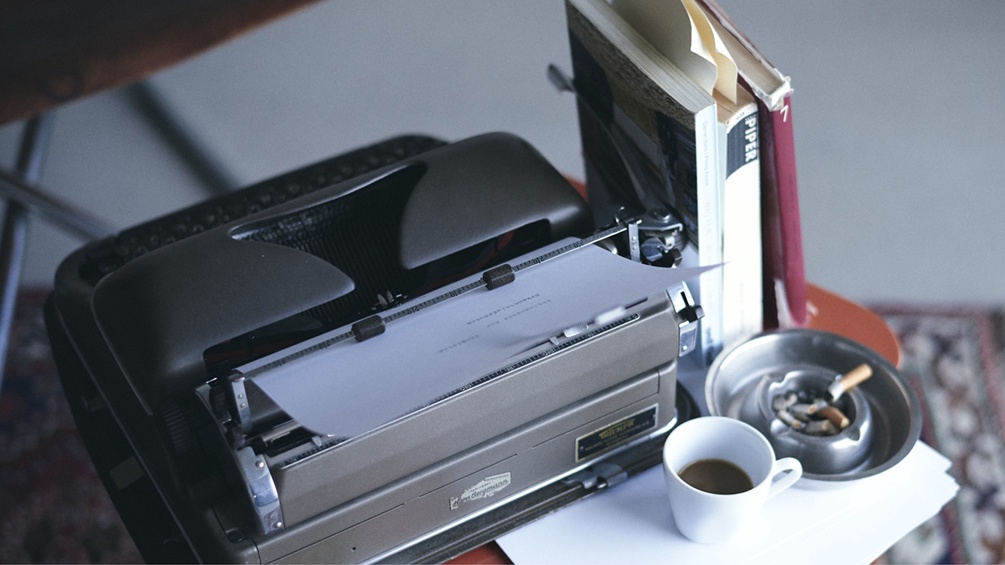 Schreibmaschine, Kaffeetasse und Aschenbecher samt Bücher