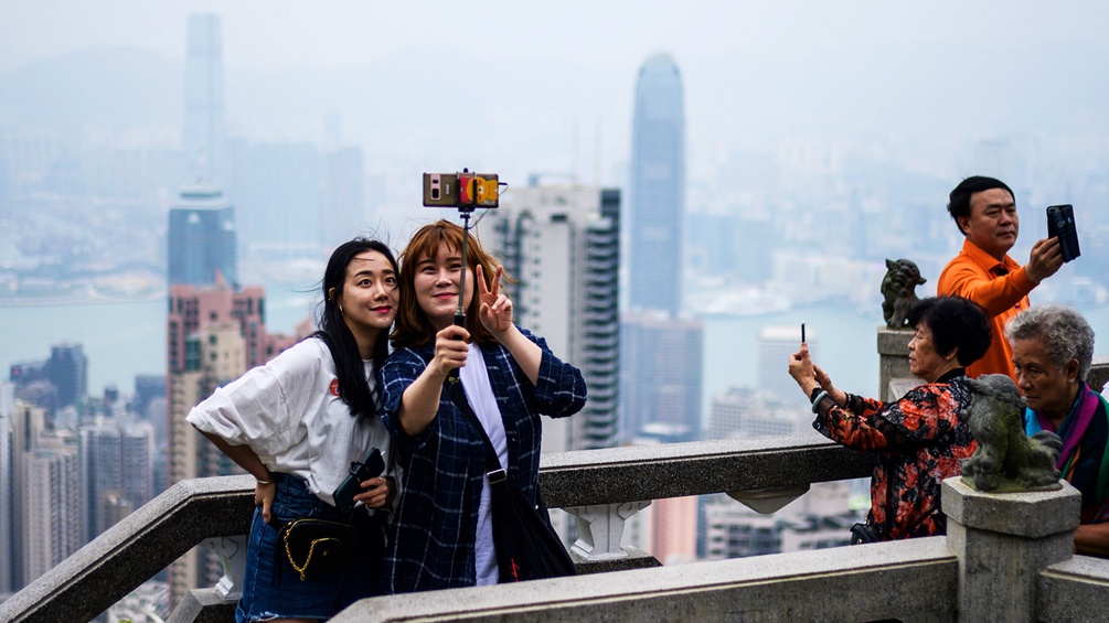 Mehrere Touristen machen Selfies auf einem Wolkenkratzer in Hongkong