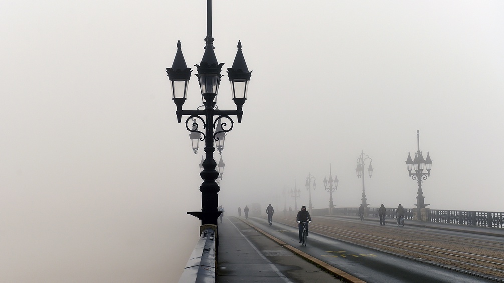 Radfahrer auf einer Brücke im Nebel
