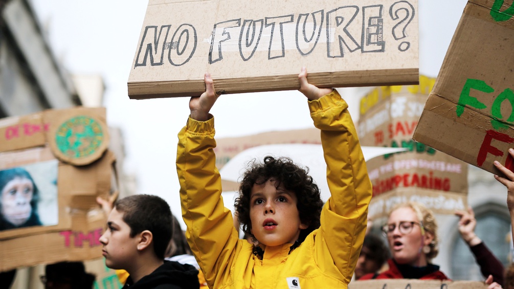 Ein Junge hält ein Schild mit der Aufschrift "No Future?" in die Luft