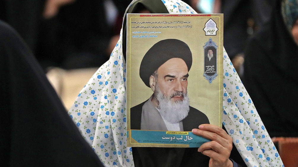 APA /STR Eine Frau hält ein Bild von Ayatollah Ruhollah Khomeini