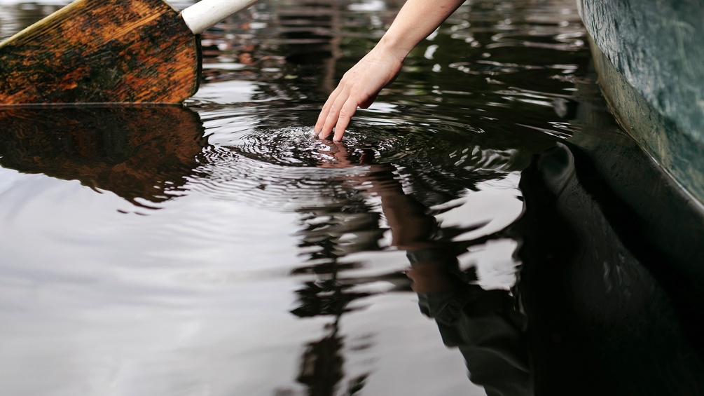 Wasserspiegelungen, Frauenhand im Wasser, Boot