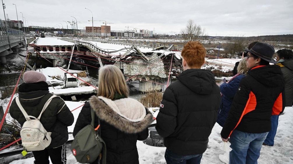 Menschen stehen in Irpin, Ukraine vor einer zerstörten Brücke