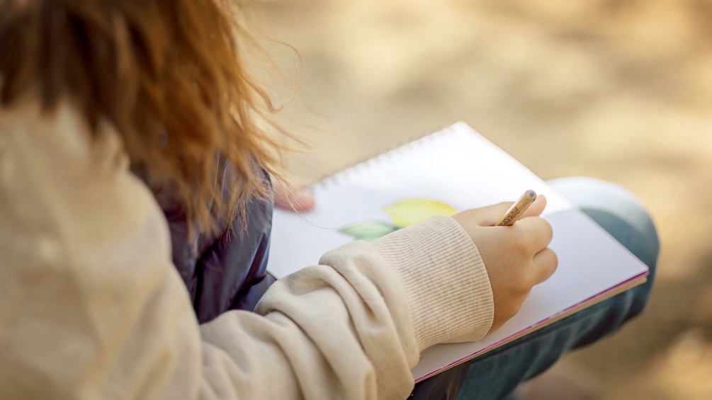Ein Mädchen zeichnet im Freien