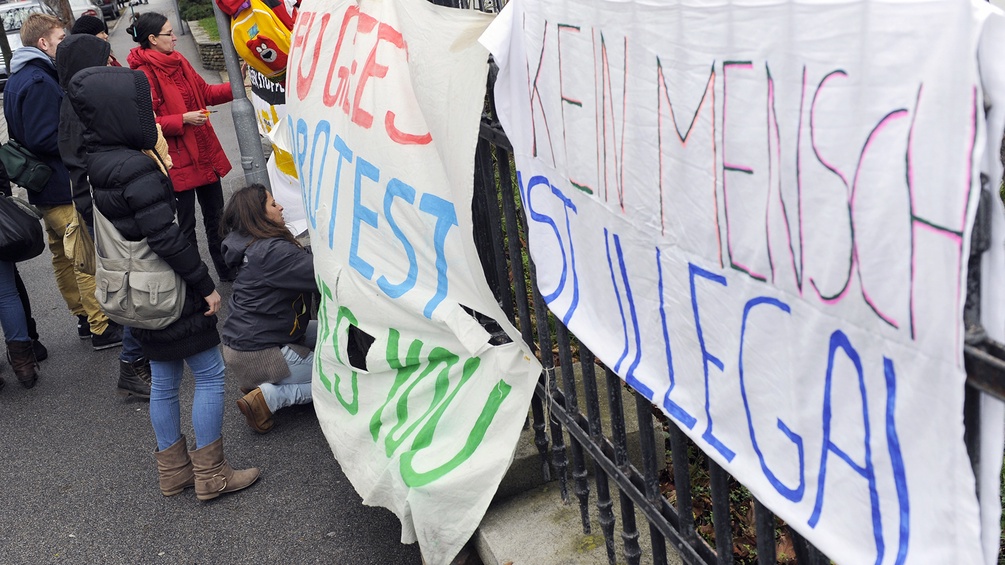 Protestanten halten Banner mit der Auschrift: "Kein Mensch ist Illegal!".