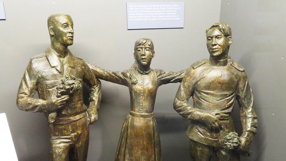 Statue: Zwei Soldaten, dazwischen Mädchen mit ausgestreckten Armen