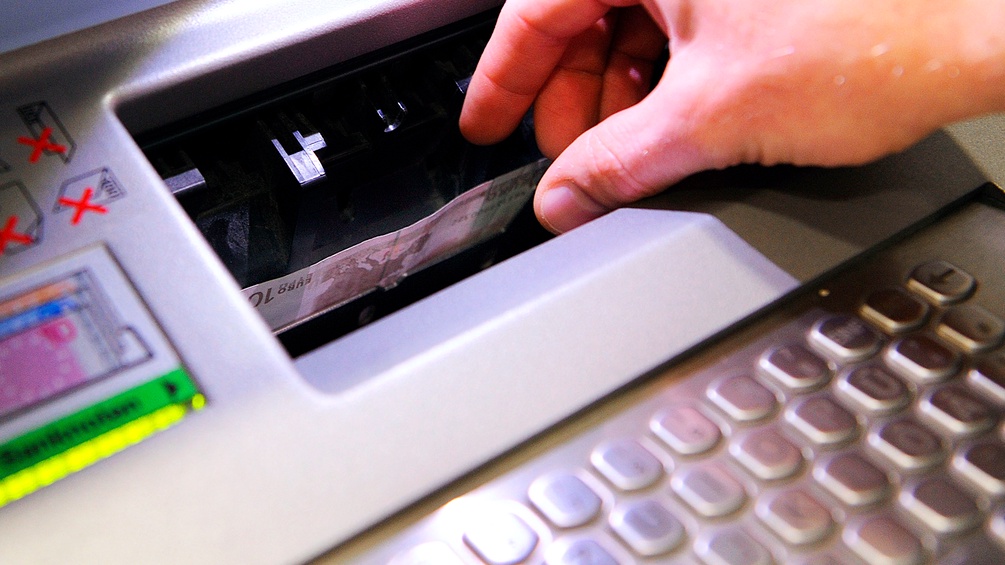 Hand nimmt Geldschein aus Automaten